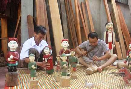 Ông Nguyễn Văn Dậu (bên trái) kiểm tra việc đục đẽo con rối