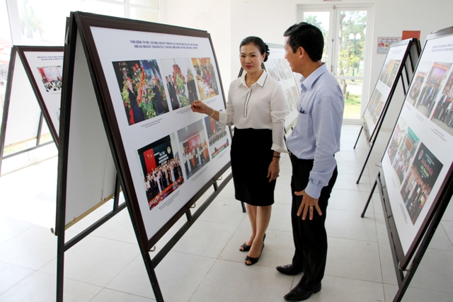 Ông Lâm văn Khang giới thiệu những bức ảnh hoạt động của Làng Văn hóa – Du lịch các dân tộc Việt Nam với bà Trương Thị Ngọc Ánh