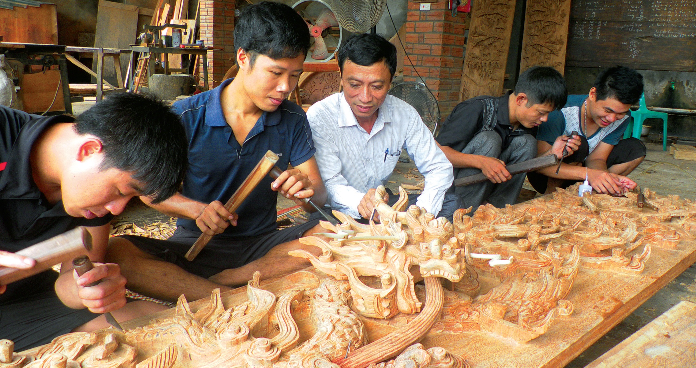 Nghệ nhân Nguyễn Khắc Tiến (áo trắng) đang truyền dạy nghề cho các thế hệ trẻ