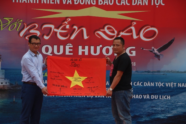 Nhà báo Lê Vĩnh Phong trao tặng Lá cờ Tổ quốc có chữ ký của các chiến sỹ đảo Nam Yết cho Giám đốc Khu các làng dân tộc Nguyễn Thanh Sơn