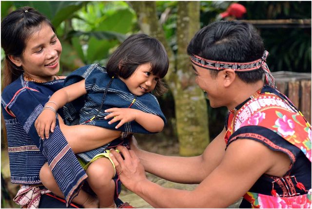 Bé Đinh Thị Ni (2 tuổi) - người được làm lễ thổi tai, đang vui đùa trong bố mẹ, chị Đinh Thị Mai và anh Đinh A Nghinh 