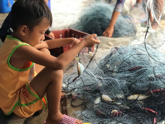 Trẻ con gỡ lưới thu hoạch cá khi thuyền cập bến
