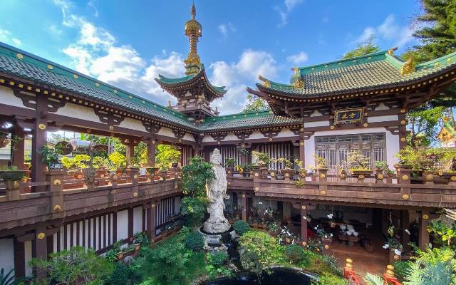 Một tiểu cảnh bên cạnh chánh điện được trang trí với tượng Phật, hồ nước, cây cảnh, bonsai và hành lang xung quanh