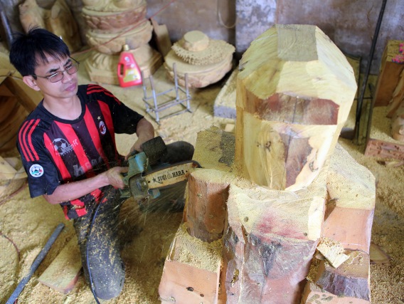 Anh Nguyễn Văn Chung người dân làng Dư Dụ đang làm công đoạn xẻ gỗ tạo hình khối cho một bức tượng